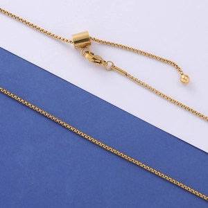 Macro shot of adjustable golden box chain with lobster clasp and sliding bead detail