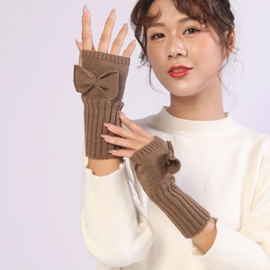 Detail of brown knitted fingerless gloves showing a delicate bow and woven texture