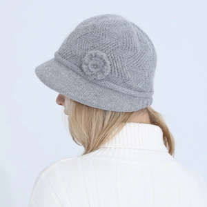 Detail of gray knitted hat showing fuzzy floral accent and wavy crochet texture