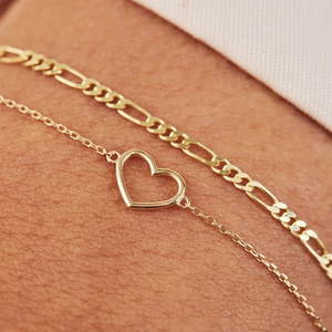 Macro detail of a 925 silver gold-plated heart pendant and Figaro chain on skin