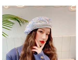 Detailed macro view of vibrant iridescent sequins on a white fashion beret hat texture