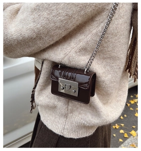 Detailed close-up of mini glossy leather bag with silver chain strap and metal lock