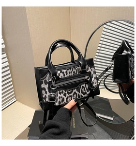 Detalle de un bolso con estampado de leopardo, adornos de cuero negro y cremallera de metal
