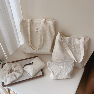 Detailed view of beige lace embroidery fabric set including tote bags and accessories