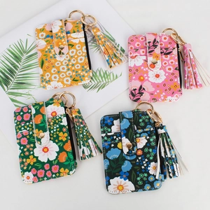 Detailed flat lay of floral zip card holders with tassels and gold ring clips