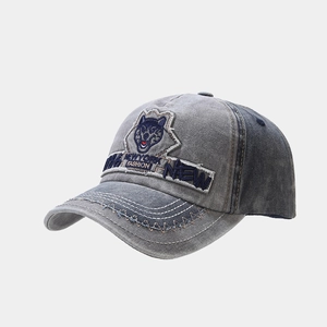 Detail of grey and blue washed cotton baseball cap with wolf embroidery and stitching