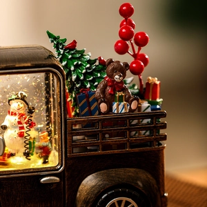 Close-up of vintage Christmas snow globe truck with Santa, bear and glowing snowman detail