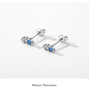 Macro detail of S925 sterling silver studs with three claw-set blue and clear zircons