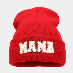 Detail of red knitted beanie featuring golden sequin MAMA letter patches and soft ribbed texture