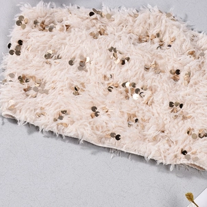 Dettaglio di finta pelliccia beige con paillettes dorate decorative e texture morbida