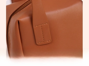Detailed view of precise stitching on premium brown PU leather shell cosmetic bag handle