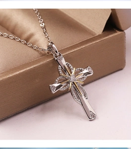 Detail of silver cross pendant with gold starburst and clear crystal on a fine chain