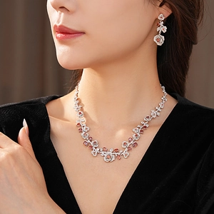 Close-up of vintage floral necklace and earrings set with red and clear crystals