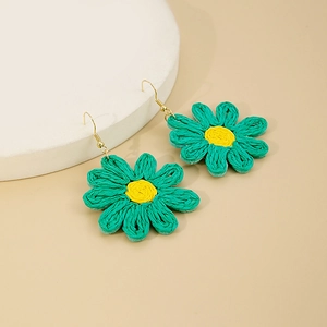Détail de boucles d'oreilles marguerites en raphia vert fait main et crochets dorés