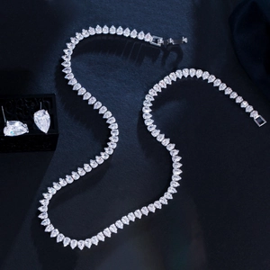Macro shot of silver bridal jewelry set with pear-cut zircon necklace and stud earrings