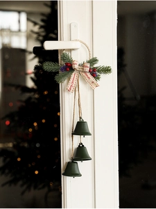 Detail of Christmas metal bells with red berries and pine needles hanging on a door handle