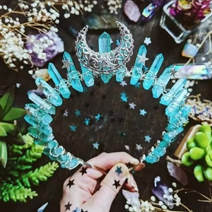Detail of blue crystal crown with silver moon and star accents on dark wood