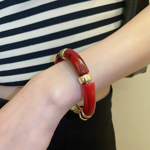 Détail d'un bracelet géométrique en acrylique rouge avec intercalaires dorés au poignet