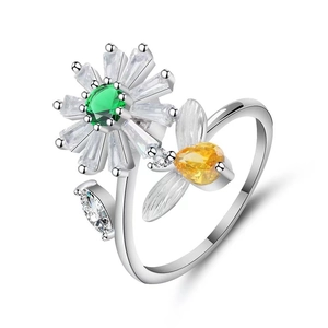 Macro shot of silver sunflower and bee spinner ring featuring green and white zircons
