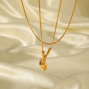 Close-up of golden 18k teardrop necklace with heart detail on elegant silk fabric