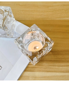 Macro detail of Nordic glass candle holder with ice crystal texture and warm candle flame