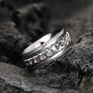Macro shot of silver stainless steel rotating chain ring on black rock background