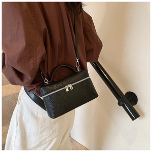 Close-up of black lychee textured leather box bag with silver zipper and shoulder strap