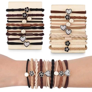 Detail view of woven elastic hair ties with heart and floral charms on a model's wrist