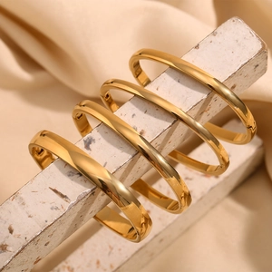 Bracciali in acciaio inossidabile placcato oro 18K da 4mm esposti su un supporto in pietra