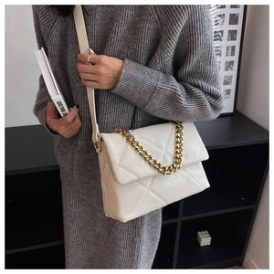 Detail van witte gewatteerde crossbodytas met gouden ketting en ruitjestextuur