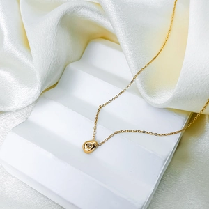 Elegant gold necklace with a teardrop zircon pendant on a minimalist white display