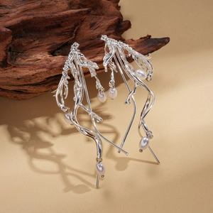 Irregular twisted geometric silver earrings with pearls on a natural wood background