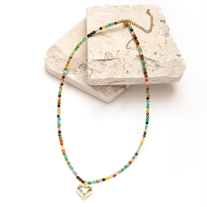 Detailed close-up of a bohemian beaded necklace with a golden heart pendant on stone decor