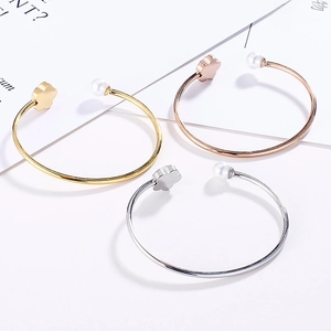 Detailed view of three-color minimalist bracelets with white pearl and clover charm details