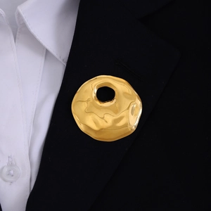 Golden irregular hollow texture brooch pinned on a black suit blazer lapel