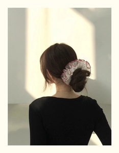 Vue détaillée d'un chouchou en dentelle fleurie porté en chignon pour un style haut de gamme