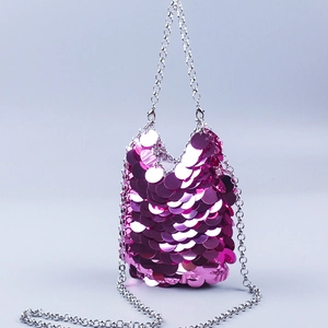 Close-up of sparkling magenta sequin handbag with silver metal chain shoulder strap