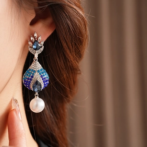Dettaglio della modella che indossa orecchini pendenti vintage con perle blu pavone
