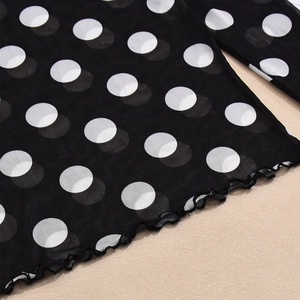 Nahaufnahme des schwarzen Netzhirts mit weißen Punkten und Rüschensaum-Detail