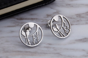 Detailed view of silver bird on branch earrings with vintage circular hollow metal design