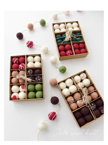 Detailed view of assorted wool felt Christmas balls in organized gift boxes with twine