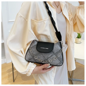 Detail of denim and leather patchwork crossbody bag with decorative metal flower chain