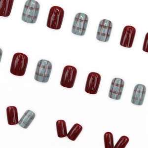 Short square press-on nails in deep red and plaid patterns with a glossy finish