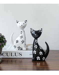 Détail de figurines de chats nordiques noir et blanc avec motifs floraux sur bois