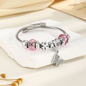 Close-up of crown charm bracelet with pink crystal beads and butterfly pendant on stone