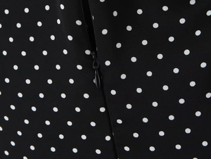Détail de la fermeture éclair invisible et de l'imprimé à pois blancs sur tissu noir