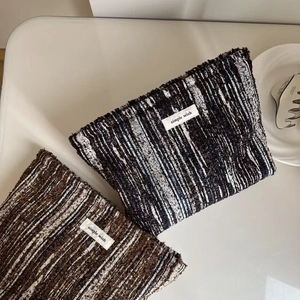 Close-up of textured tweed makeup bags with fringe edges and simple wish labels