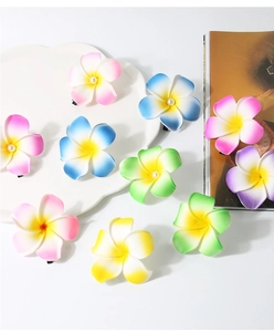 Close-up of colorful EVA frangipani flower hair clips with pearls on a white tray