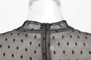 Detail of high stand collar and back zipper on black mesh polka dot dress