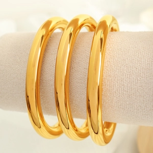 Set of three golden titanium steel C-shaped round bangles with polished smooth finish